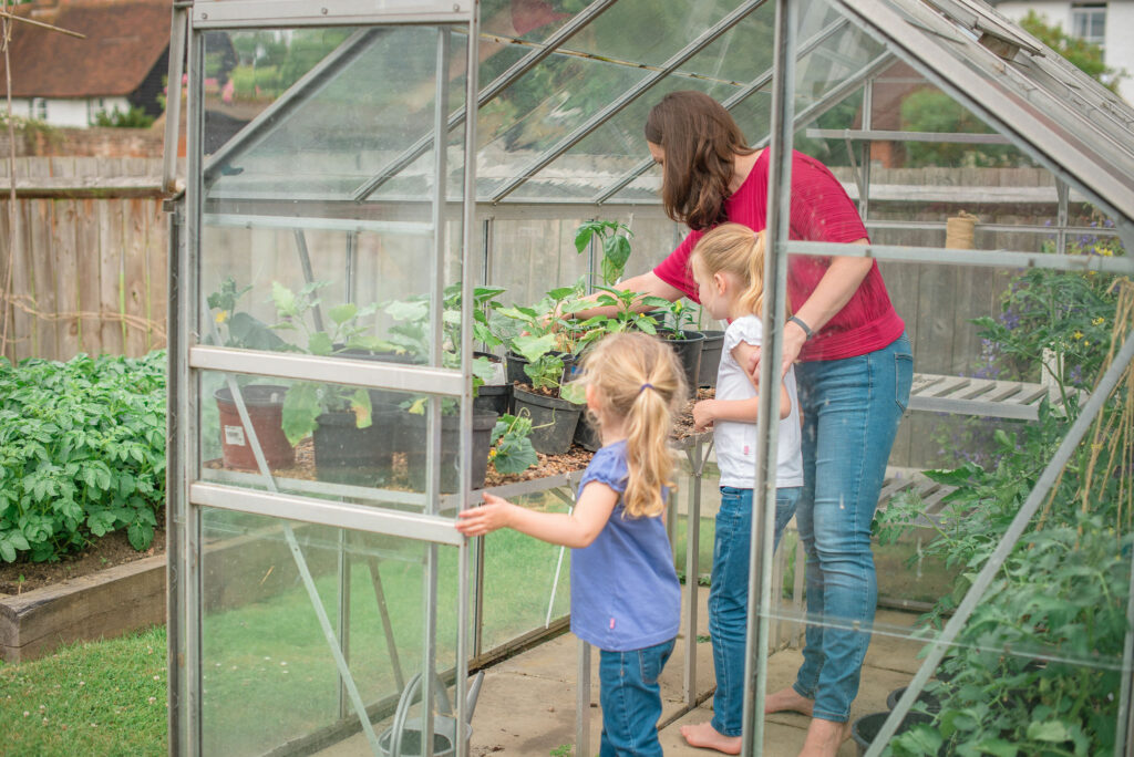Emma and children look at the plants in the greenhouse.