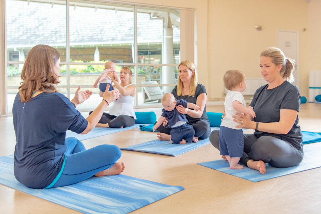 Mums in yoga class sitting on mats holding their babies